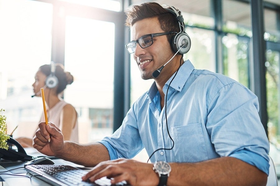 man talking to customer wearing headphones in office