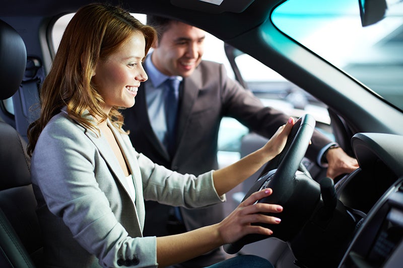 Salesperson with happy customers in car